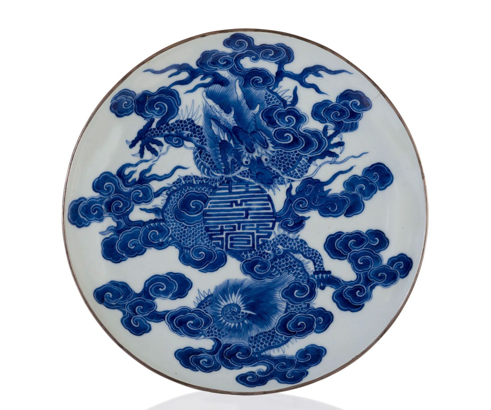 Assiette impériale en porcelaine à décor bleu blanc dit « bleu de Huế » figurant un dragon pentadactyle dans les nuées protégeant un symbole Tho (longévité) et Khanh (prospérité) prenant la forme d'un médaillon, Chine pour le Vietnam, seconde moitié du XVIIIe siècle. Porcelaine à décor bleu blanc, 26 cm. Marque à quatre caractères en bleu sous couverte sous la base « Khánh xuân thị tả » soit « Célébrer le Printemps, palais de Gauche ». Estimé : 80 000/120 000 €. © Lynda Trouvé
