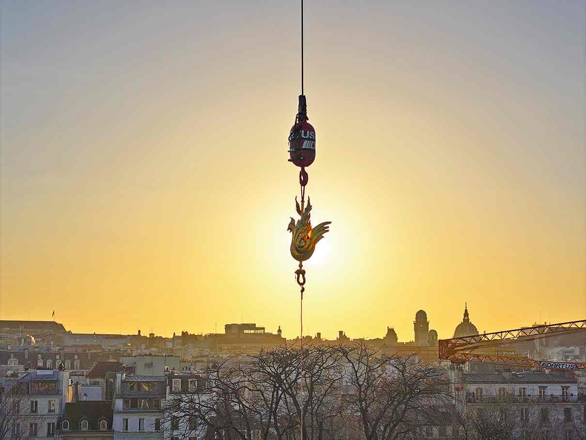 Le 16 décembre dernier, après avoir été béni par Monseigneur Ulrich, le nouveau coq en cuivre doré dessiné par l’architecte en chef Philippe Villeneuve s’élève au-dessus de la forêt d’échafaudages pour rejoindre le sommet de la flèche. © Rebâtir Notre-Dame de Paris