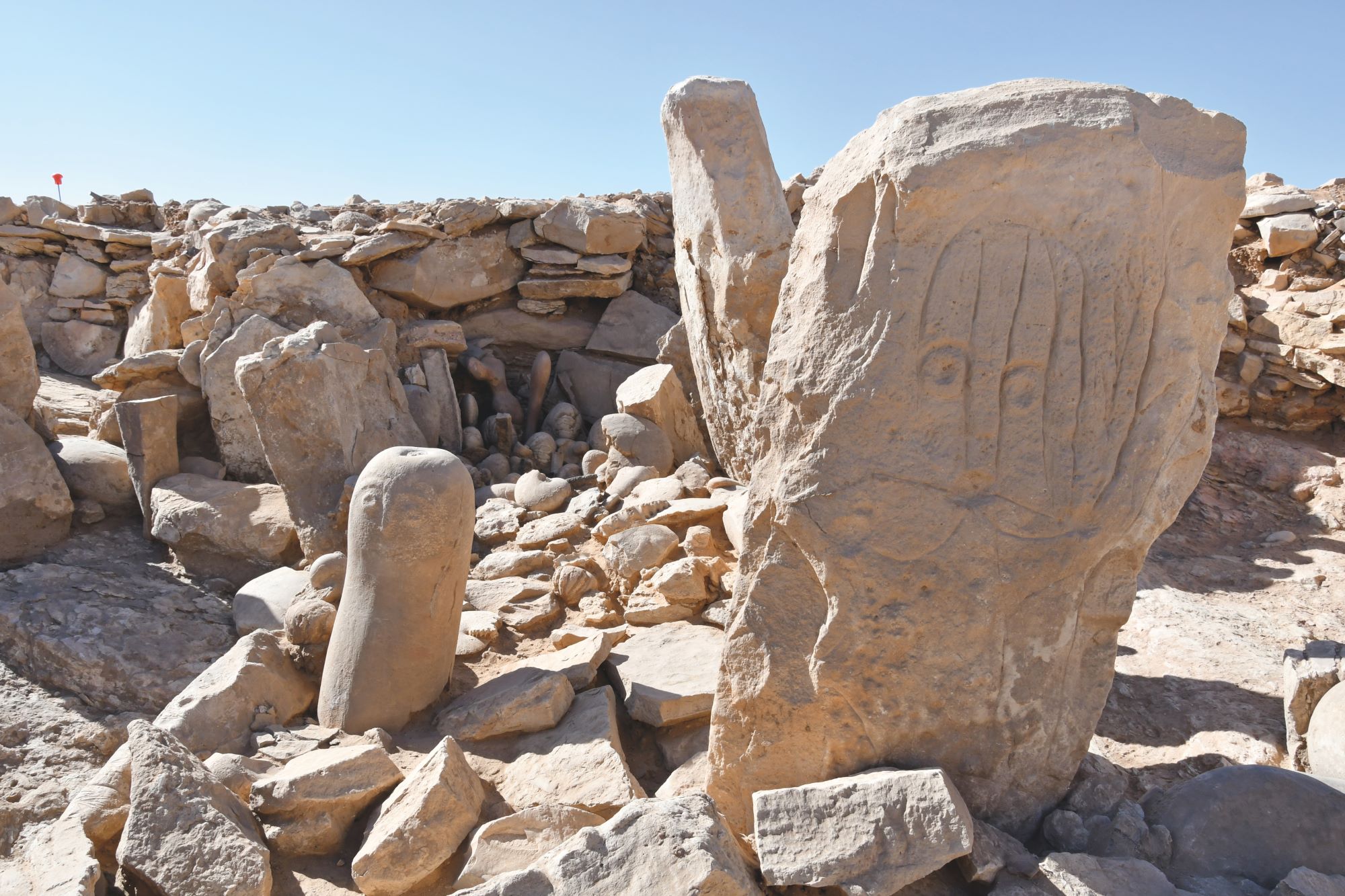 Les deux stèles dressées dites de « Abu Ghassan » et de « Ghassan », et le dépôt rituel de fossiles marins à l’arrière-plan, sur le site JKSH P52, Khashabiyeh. © Mission archéologique du sud-est jordanien